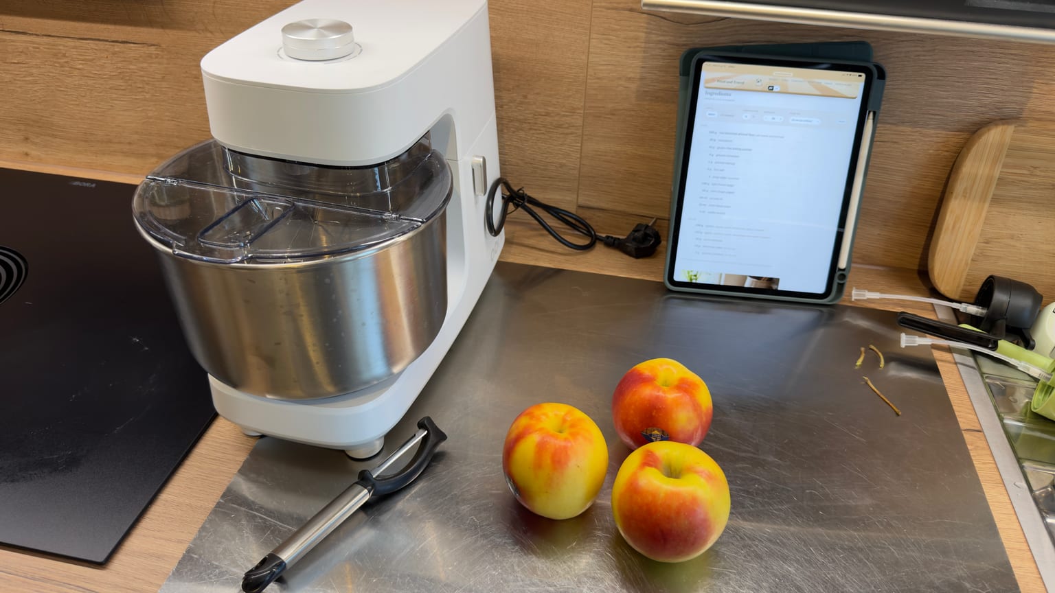 Apples, a peeler, and a stand mixer on the counter, ready to start Christoph's upside-down apple almond cake
