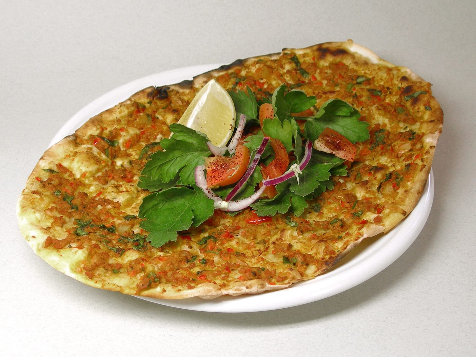 Lahmacun: Turkish thin flatbread with spiced topping served as a natural-light editorial food photograph