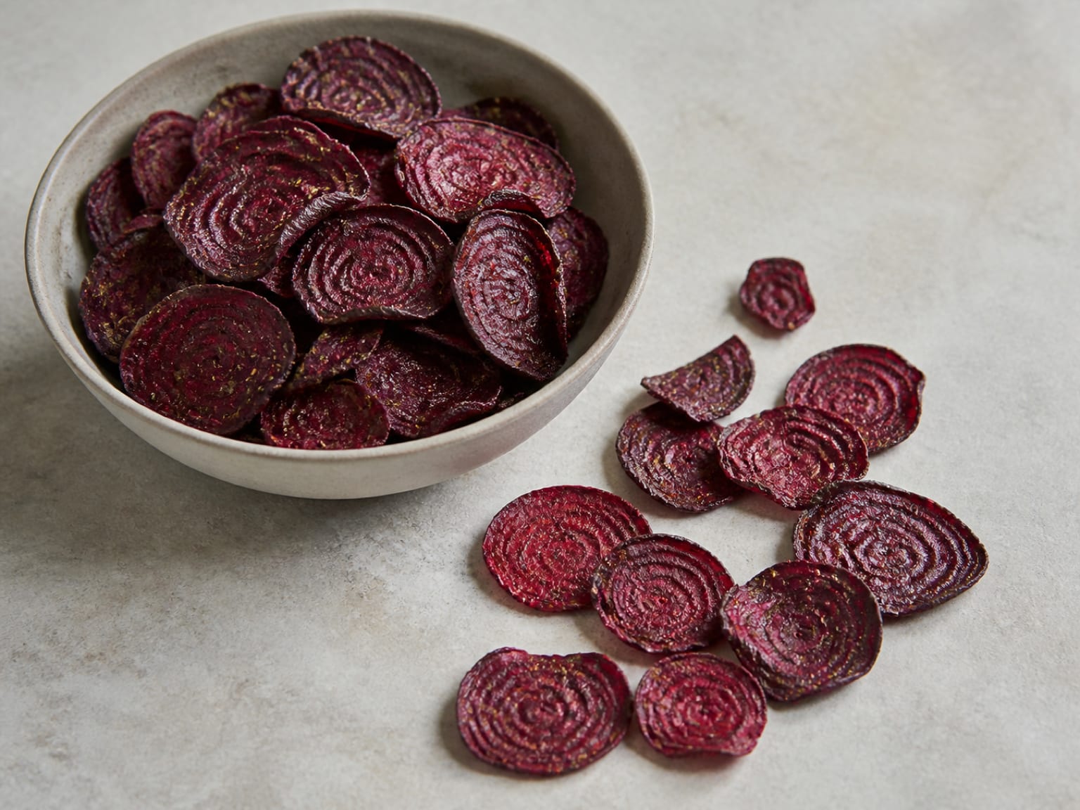 Deep ruby beet crisps with curled edges and a fine rosemary coating