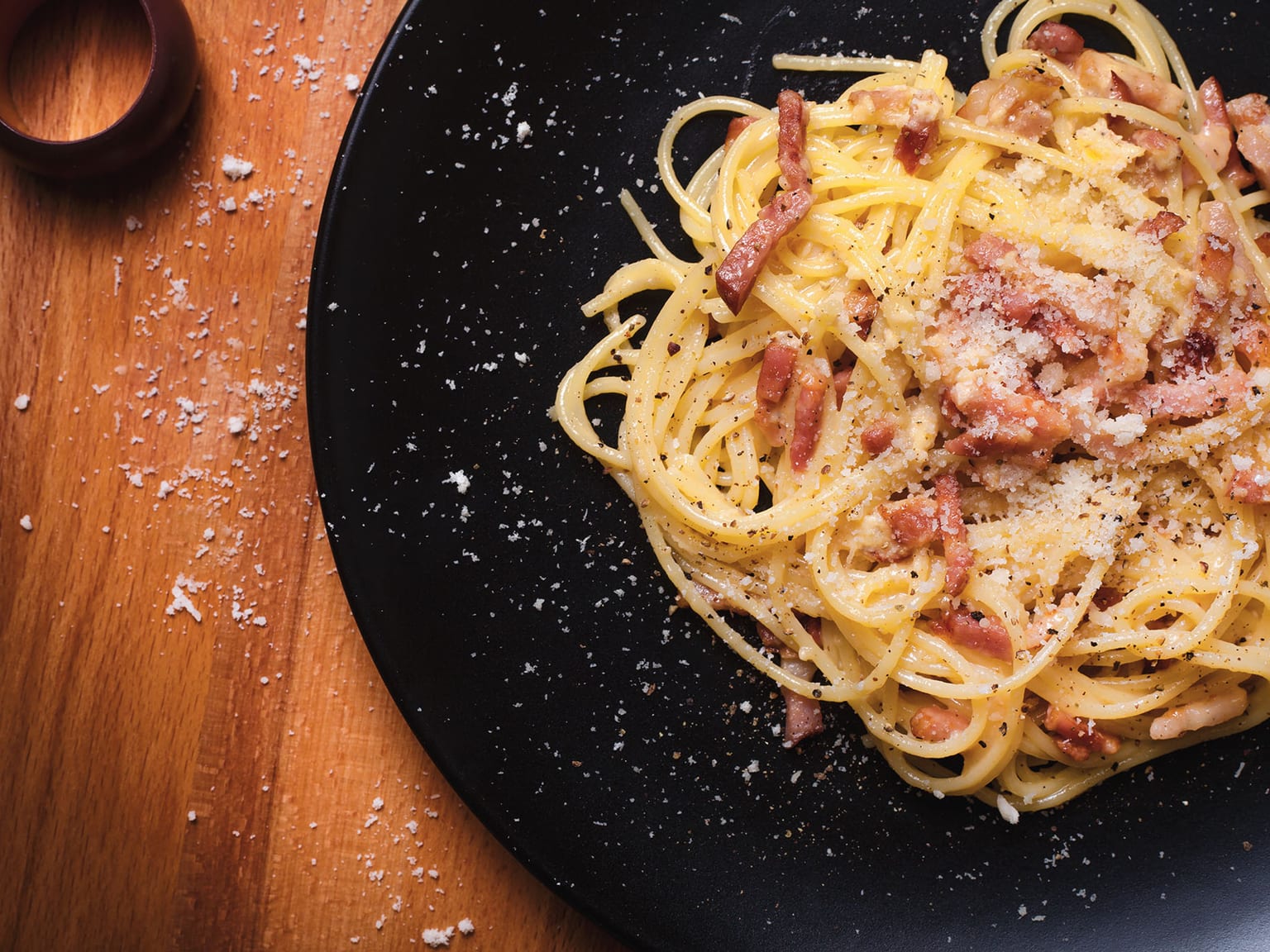 Glossy spaghetti carbonara with crisp golden guanciale, Pecorino Romano, and coarse black pepper